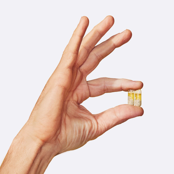 Closeup image of man holding 2 Essential for Men 50+ pills in hand