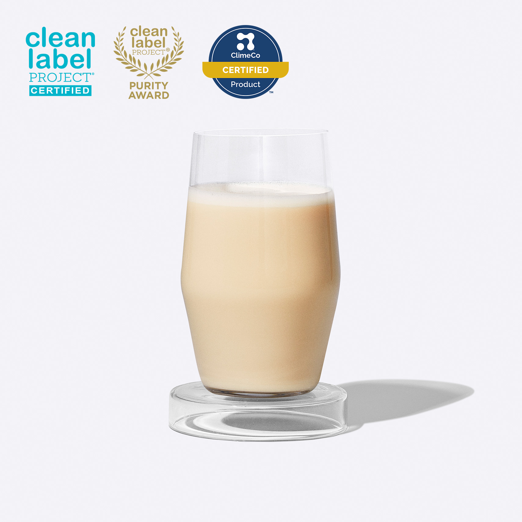 Glass of Essential Protein Daily Shake on a grey background with three certification badges