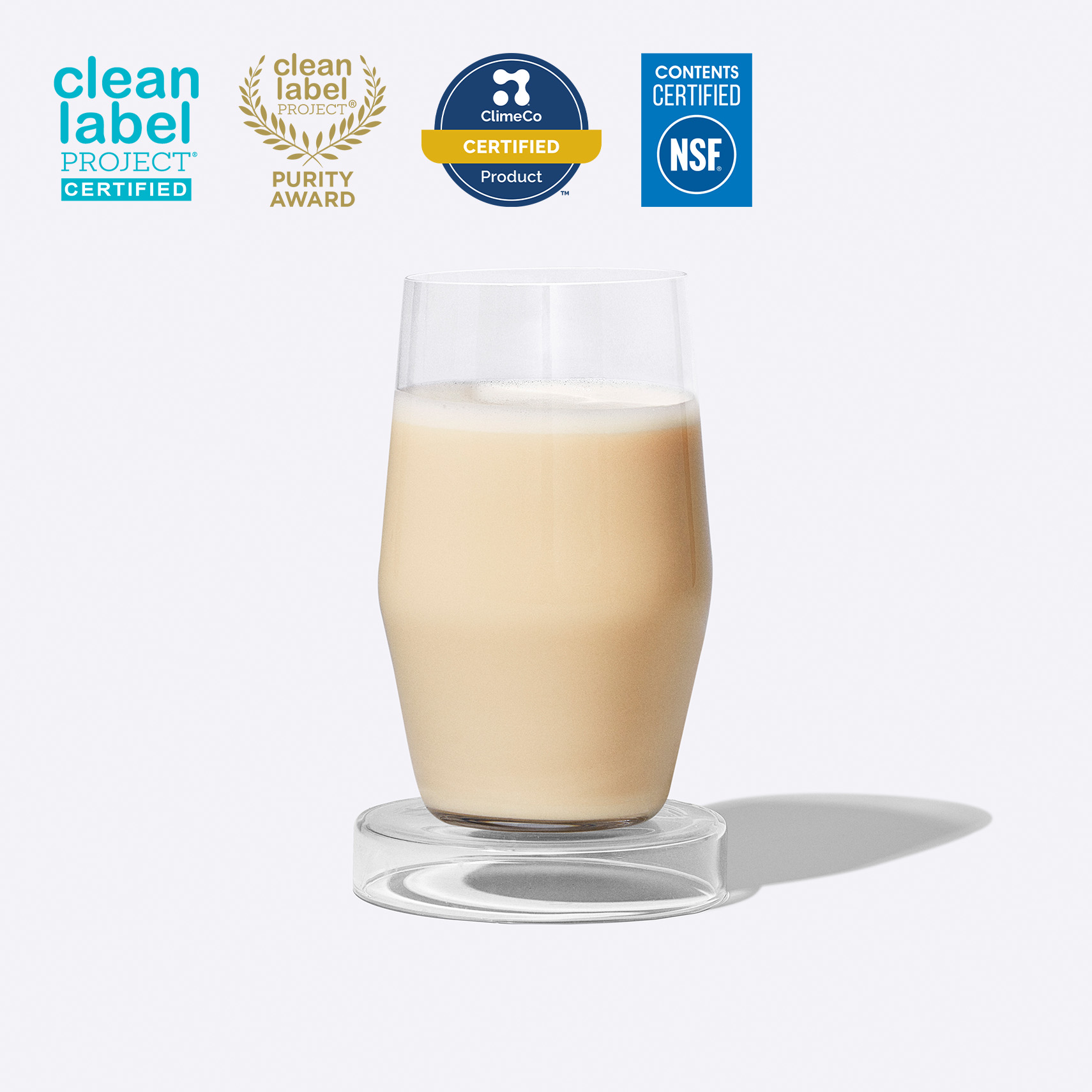 Glass of Essential Protein Daily Shake on a grey background with three certification badges