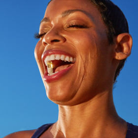 Smiling woman with 50+ multivitamin in between her teeth