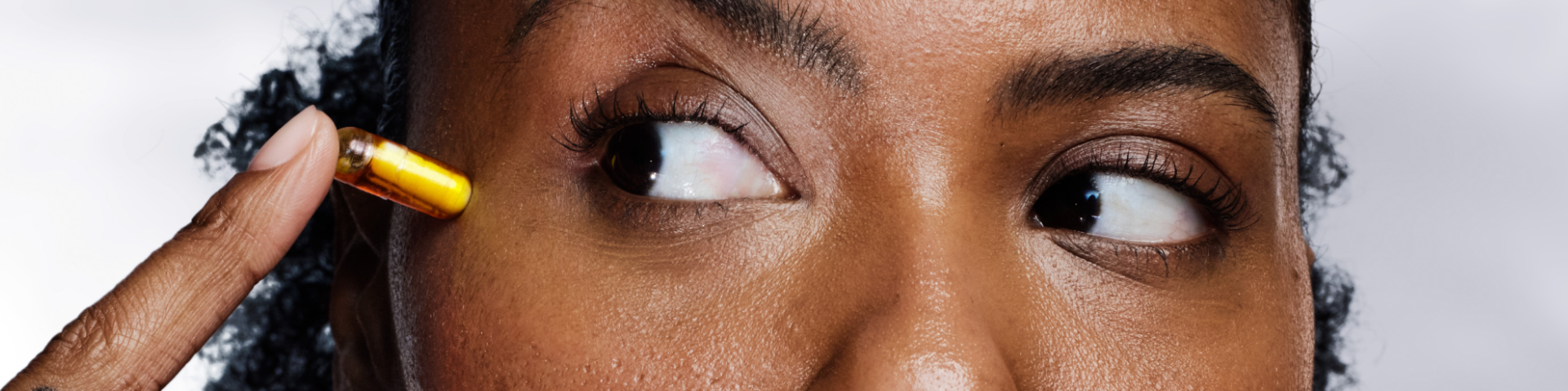 Woman looking at a HyaCera™ capsule on her skin.