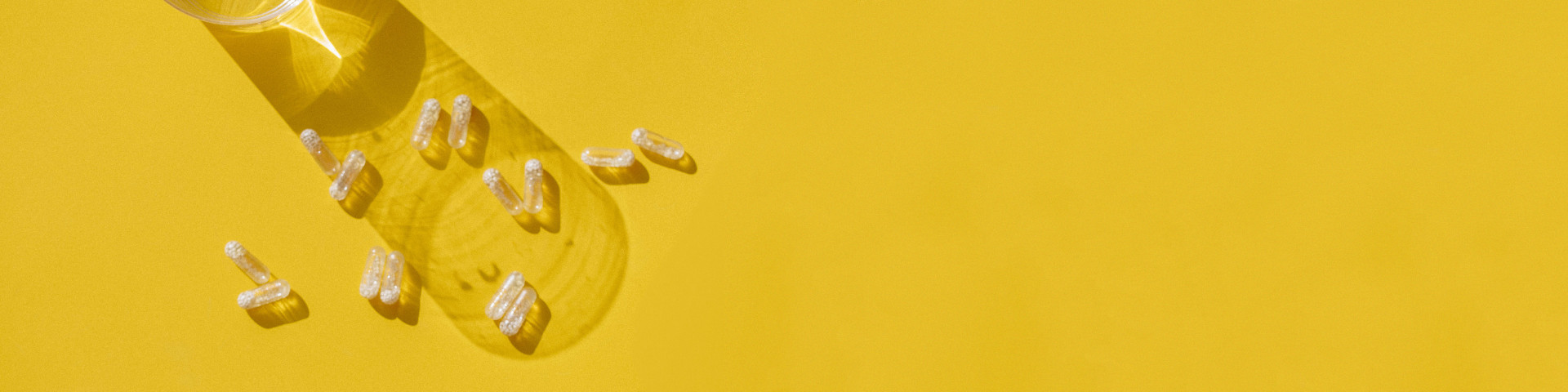 Several prenatal vitamins scattered on a yellow background.
