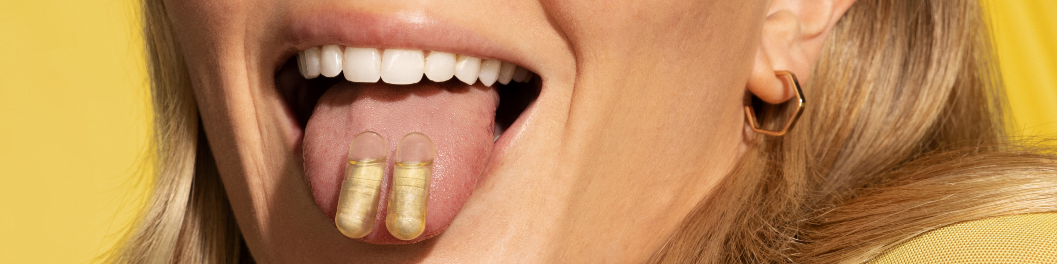 Two prenatal vitamins on a woman's tongue.
