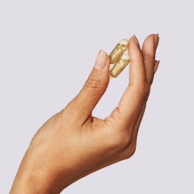 Photo of a hand holding two Ritual Essential Prenatal multivitamins