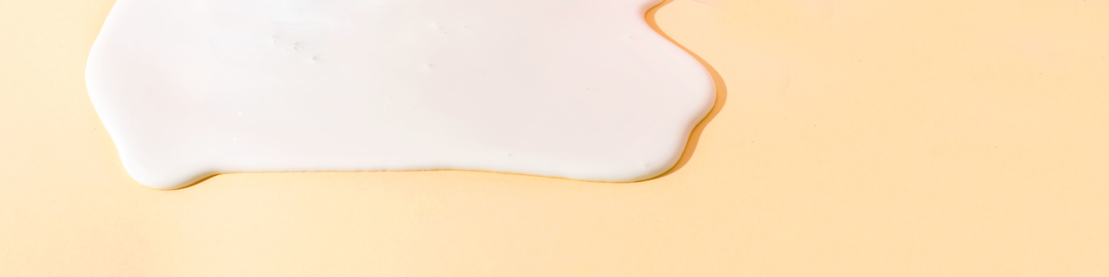 Closeup of calcium as a white liquid on a peach-colored background.