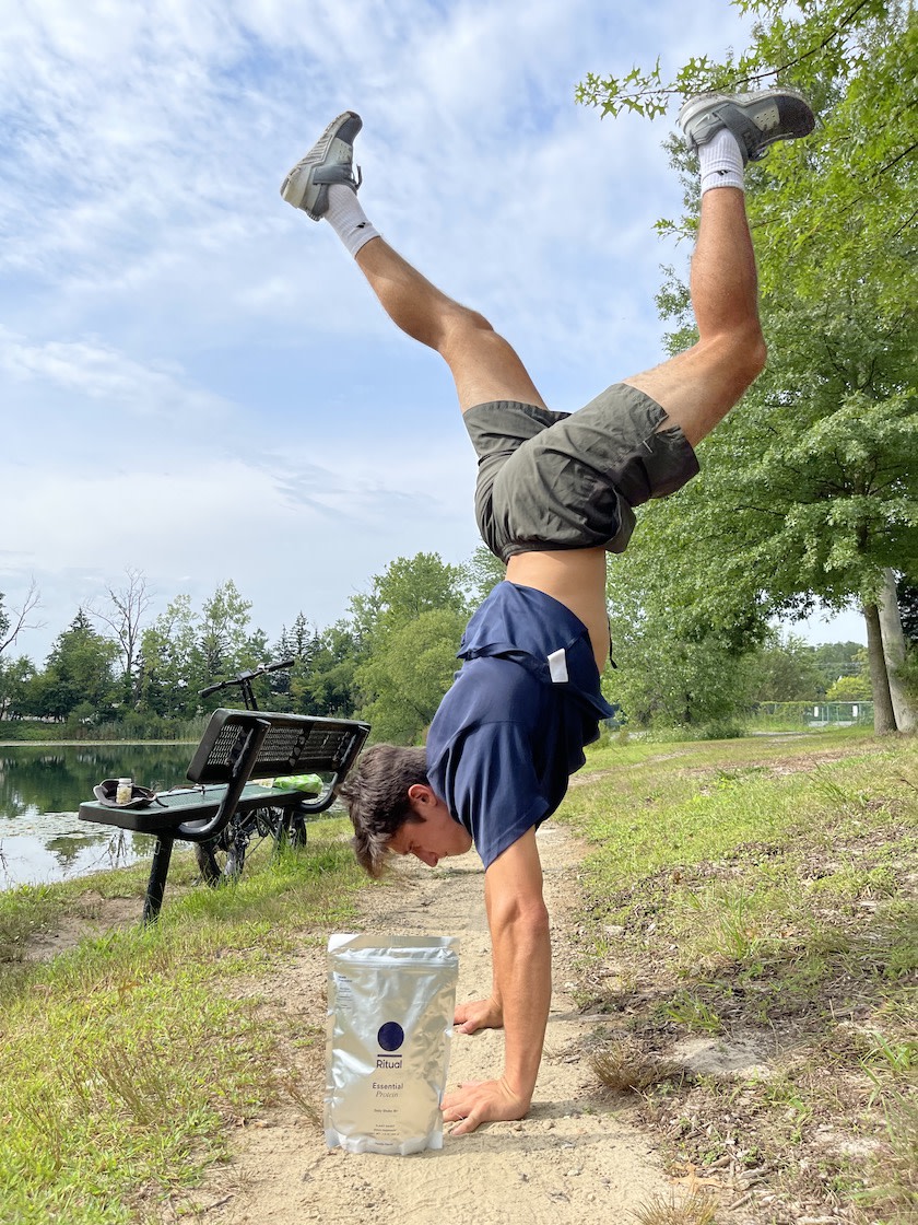 Ritual community member doing a handstand over an Essential Protein bag.