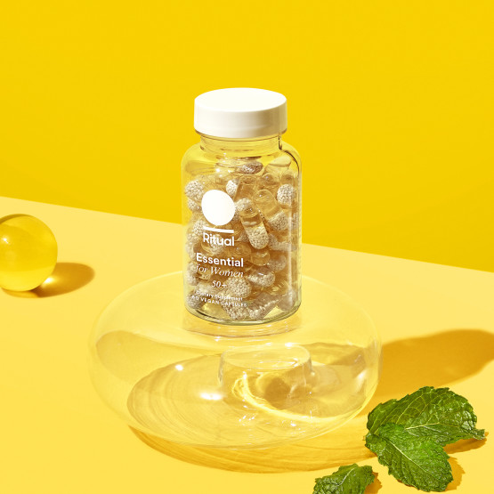 Essential for Women 50+ Multivitamin Bottle staged against yellow backdrop