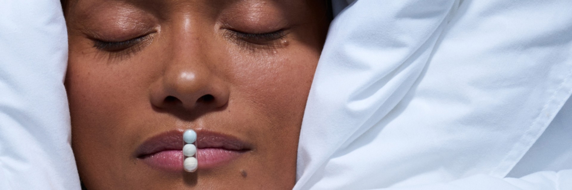 Woman sleeping with Ritual's Melatonin capsule on her lips.