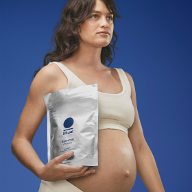 Pregnant woman posing with a package of Ritual protein powder