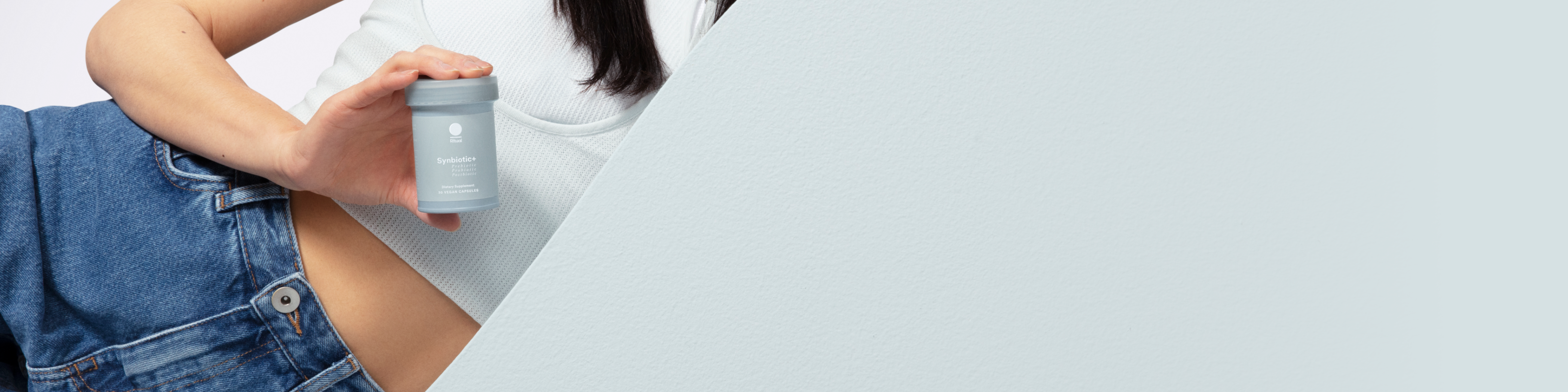 Person holding a bottle of Synbiotic+ near their stomach.