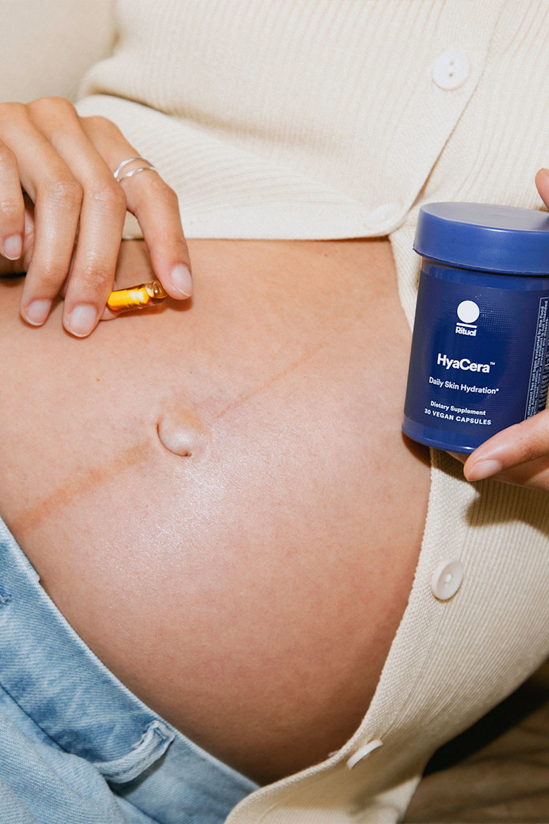 Pregnant model holding a capsule of HyaCera™ and bottle next to her belly.