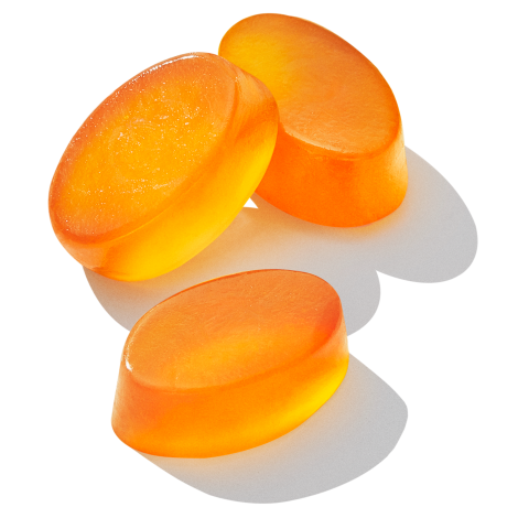 Close-up image of three (3) Essential for Kids gummies. They are oval and orange in color.