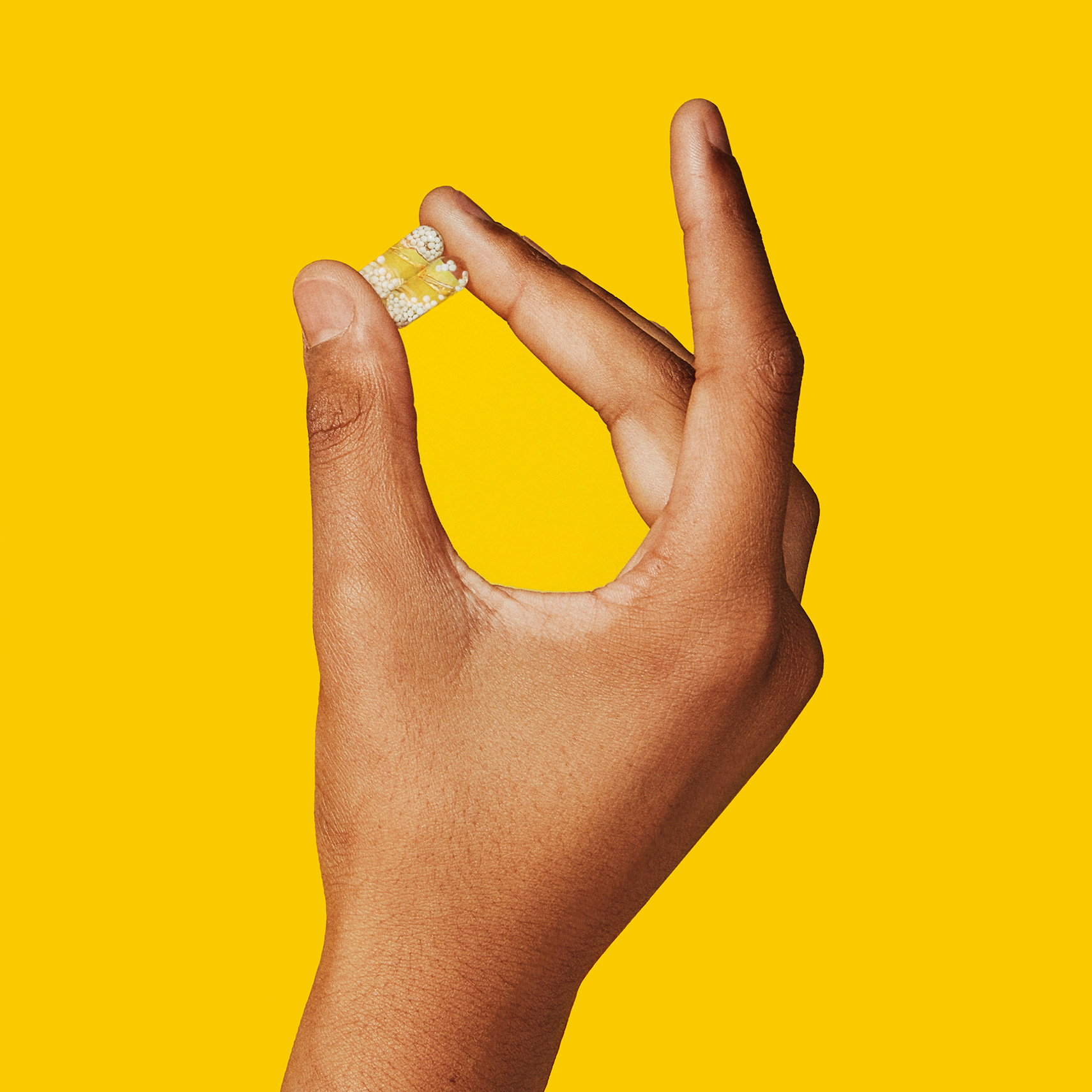 Closeup image of teen model holding 2 Essential for Teens (Him) pills in hand
