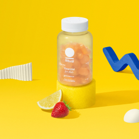 Essential for Kids Multivitamin 4+ bottle staged with a strawberry and a lemon wedge.