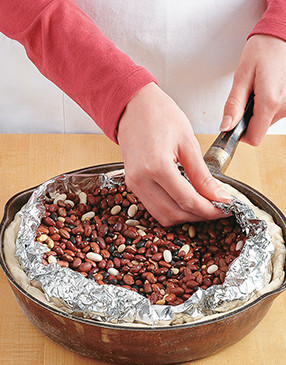 To prevent collapsing during prebaking, line the crust with foil, fill it with beans, and fold in the edges.