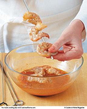 Thread marinated shrimp onto skewers, going through the tail and head to hold them in place.