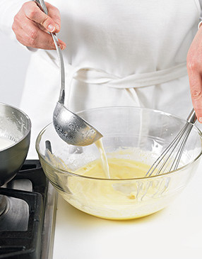 To avoid curdling, temper the egg yolks by slowly adding some of the steaming milk mixture while whisking constantly.