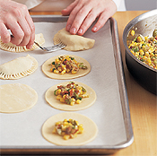 Use a fork to crimp the edges of the empanadas so they'll stay sealed and won't pop open during baking. 