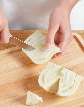 Slice the fennel bulb in half, trim off the root end, cut out the core, and slice into long, thin strips to dice.