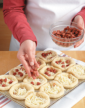 Fill the parbaked dough cups with pizza toppings, then place the cups back in the oven to finish baking.