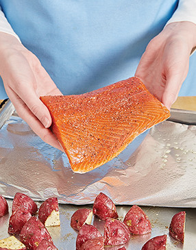 The potatoes take longer to cook, so start them first, flip them, then add the salmon and finish roasting. 
