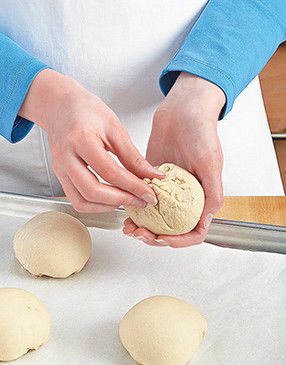To form the dough into balls, pull down the sides, tuck them under, then pinch closed to keep air out.