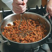 Brown the sausage over medium-high heat, crushing it with a potato masher to make the pieces finer.