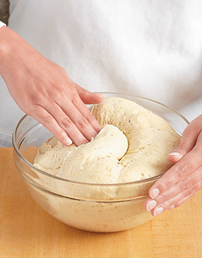 Lift the edge of the doubled dough and press out the air bubbles to redistribute the yeast cells.