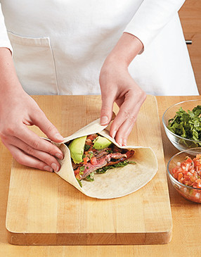 After filling each burrito, use one hand to stuff the filling into the center, then continue rolling.