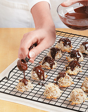Use a teaspoon measure to divide the melted chocolate topping evenly among the macaroons.