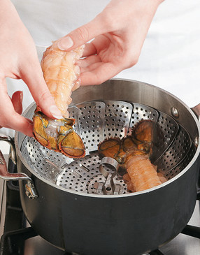 When steam begins to rise from the pan, reduce heat to low and place tails in basket; cover to cook.