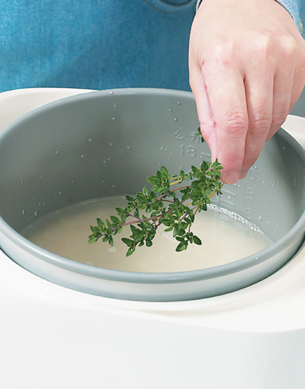 Fresh herb sprigs being added to a pot of rice. 