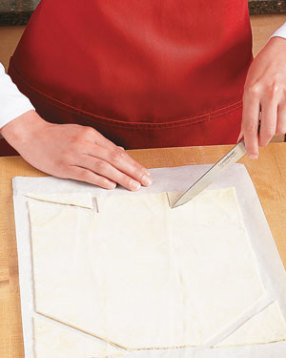 Roll pastry, transfer to parchment, then cut off top corners. Notch bottom to create end flaps.