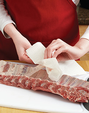 Use a paper towel to pull off the sinewy membrane on the back of the ribs. Trim away any excess fat.
