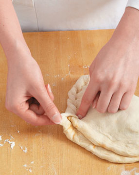 Crimp the dough by pinching a bit of bottom dough, pulling it over, and pressing it into the top to seal.