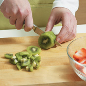 For the fruit salad, peel, slice, and chop the kiwi, and hull and slice the strawberries.