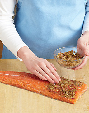 Press the rub mixture into the salmon, then place it on top of the plank on the grill.