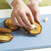 When bread is cooled slightly, rub cut side of garlic over both sides. One or two swipes is plenty.