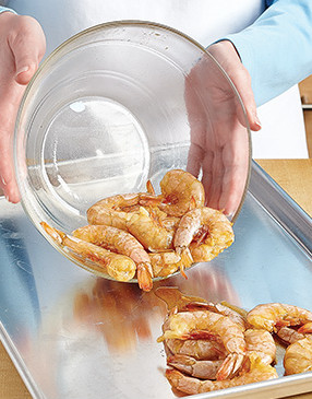 It’s fine to just dump the shrimp onto the hot baking sheet, but use a spatula to spread them out.