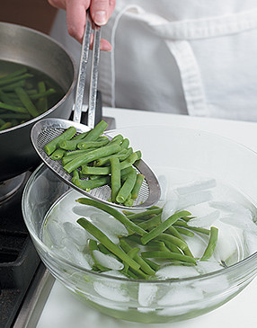 Blanch beans in boiling water, then transfer to a bowl of ice water to stop cooking and keep them green.