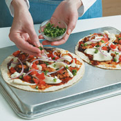 Baking pizzas on the back of a baking sheet makes it easier to remove the pizzas from the pan without bending them. Don't overload the tortillas with toppings. 
