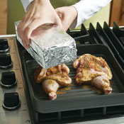 To create a seared crust and cook the meat evenly, top each half of the game hen with a foil-covered brick.