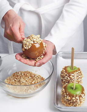 After coating each apple with caramel, use your hand to press the topping into the warm caramel.