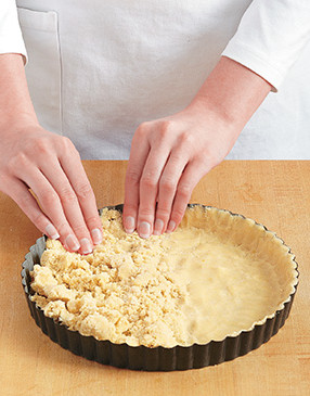 Press the dough evenly on the bottom and up the sides of the tart pan, dock, then bake.