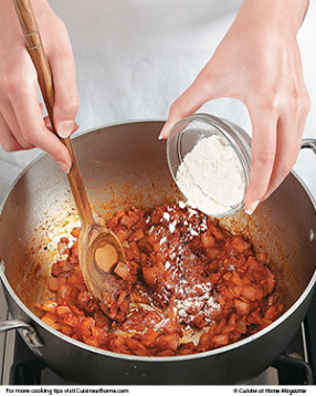 Stir tomato paste and flour into the saut&eacute;ed onions. They will help thicken the liquids into a rich sauce.