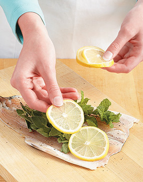 To infuse the trout with flavor, place herbs inside and arrange lemon slices in a row along one half.