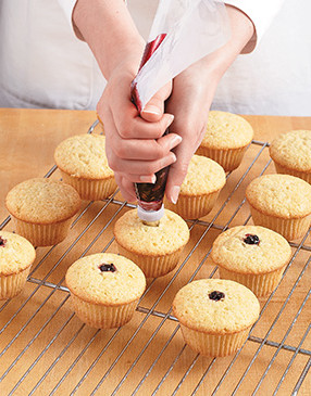 Push the pastry bag tip right into the centers of each cupcake, squeezing the jam into them.