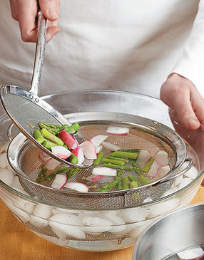 Shocking the vegetables in an ice water bath with a strainer makes them easy to remove once chilled.