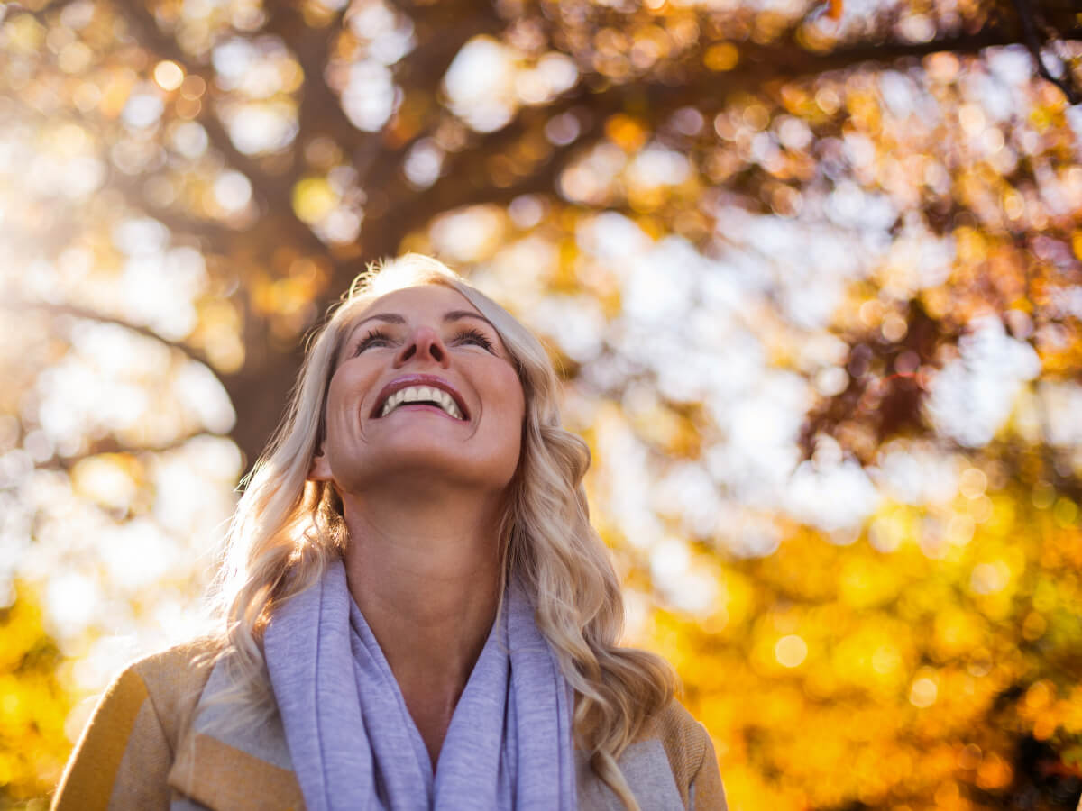 Kvinna promenerar i lövskog på hösten