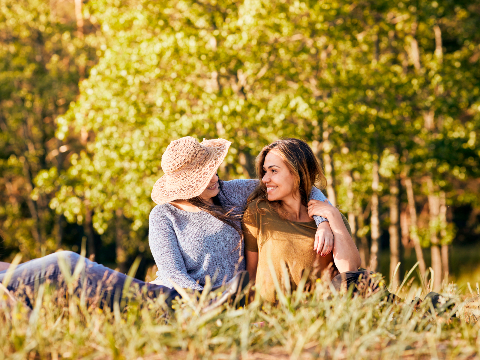 Två vänninor håller om varandra på en sommaräng
